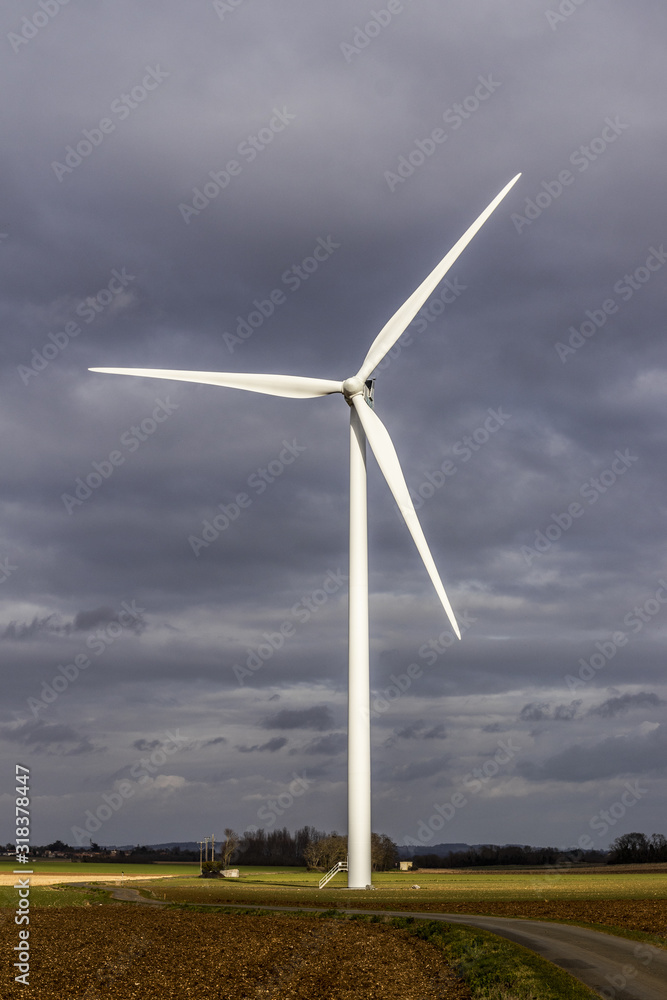 Éolienne entière durant un coucher de soleil avec beaucoup de nuages dans un champs - Parc éolien à fort impact visuel Éolienne entière durant un coucher de soleil avec beaucoup de nuages dans un champs - Parc éolien à fort impact visuel