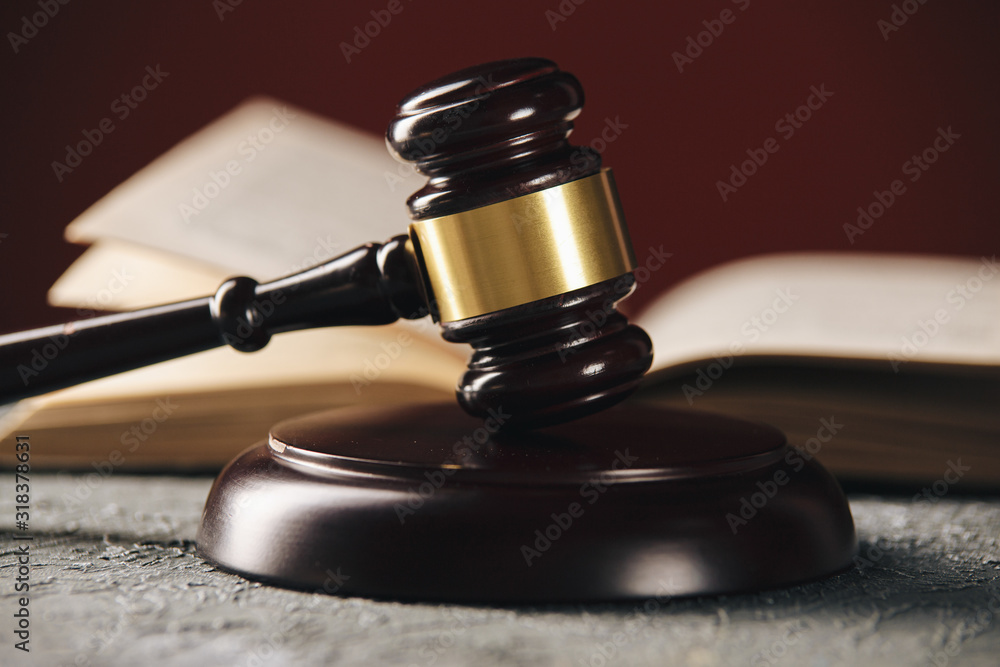 Law concept - Open law book with a wooden judges gavel on table in a courtroom or law enforcement office on black background. Law concept - Open law book with a wooden judges gavel on table in a courtroom or law enforcement office on black background.