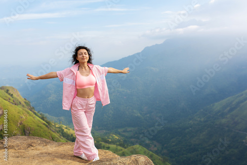 Girl enjoys a mountain view while standing on a cliff