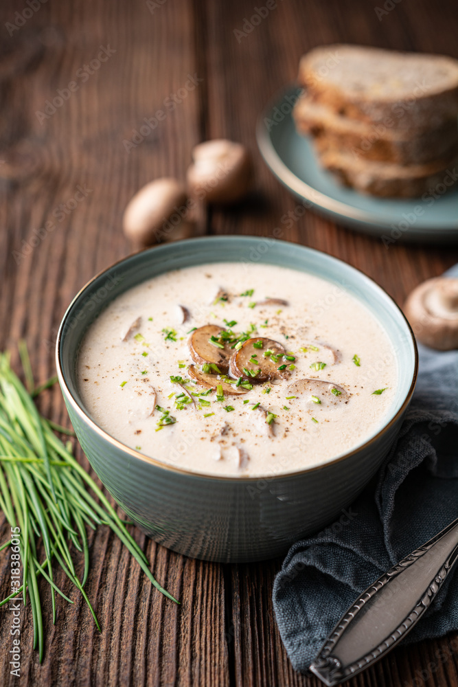 Delicious lunch, comforting Cream of mushroom soup topped with freshly chopped chives, served with crusty bread