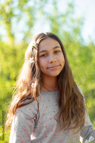 Portrait of a young beautiful teenager girl in a blooming spring green garden