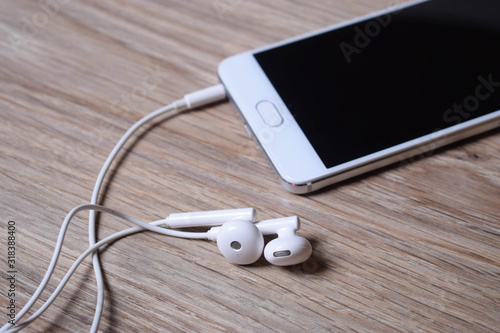 Mobile phone and earphones on wooden background