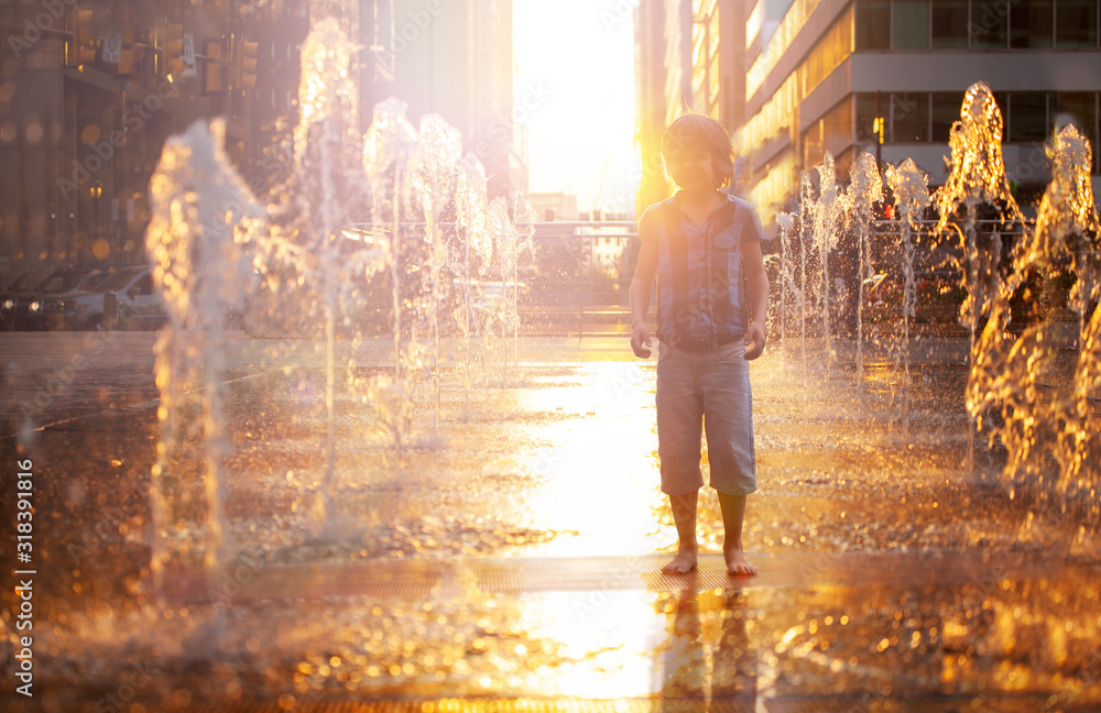 Φωτογραφία Child stand and play on street fountain on Philadelphia square over sunset near