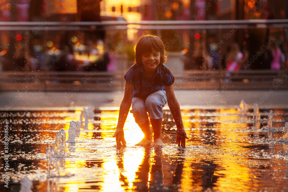 Φωτογραφία Child play with street fountain touching water on Philadelphia square over sunse