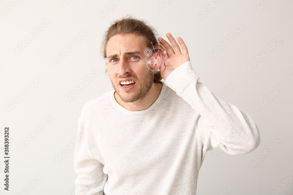 Young man with hearing problem on light background Young man with hearing problem on light background
