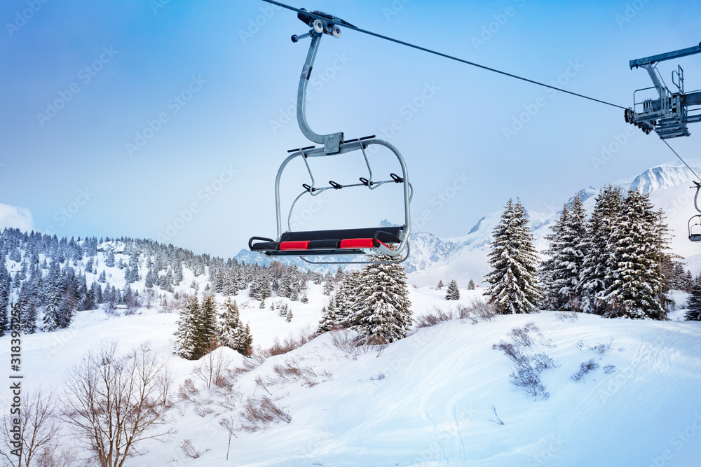 Ski lift chair on Alpine resort over fir and pine forest covered with snow after strong snowfall Ski lift chair on Alpine resort over fir and pine forest covered with snow after strong snowfall