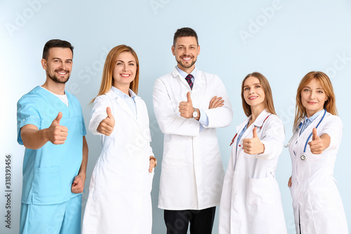Team of doctors showing thumb-up gesture on color background