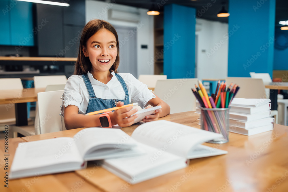 Education and school concept, happy smiling little student girl with many books at school writing. Education and school concept, happy smiling little student girl with many books at school writing.