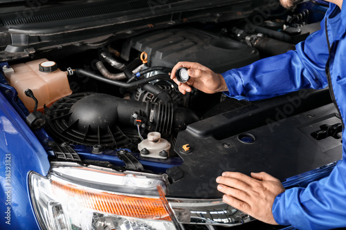 Male mechanic checking oil in car engine