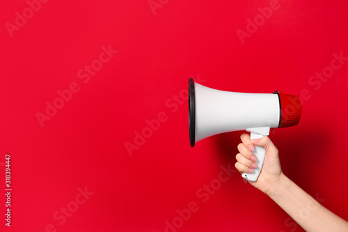 Female hand with megaphone on color background photo