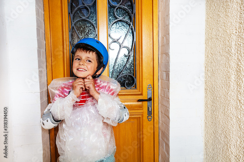 Boy fasten helmet wear super safe bubble wrap have overprotective mother standing near home door photo