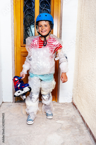 Child with rollerblades ball wear super safe bubble wrap and helmet have overprotective mother standing near home door