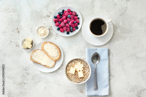 Tasty breakfast with oatmeal  fresh bread  butter  berries and cup of coffee on white background