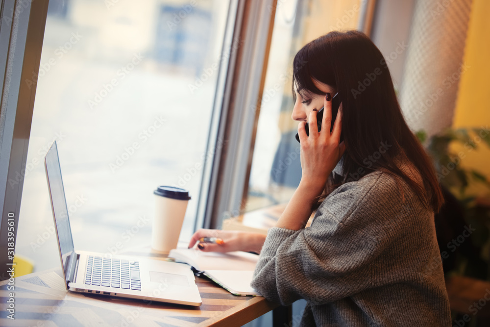 woman with laptop computer and mobile phone working in a cafe woman with laptop computer and mobile phone working in a cafe