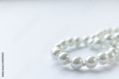 White pearls necklace on white background, clean and tidy picture, shiny pearl, close view and lots of negative space