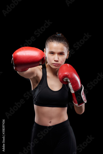Young sportswoman in activewear and boxing gloves looking at you during fight