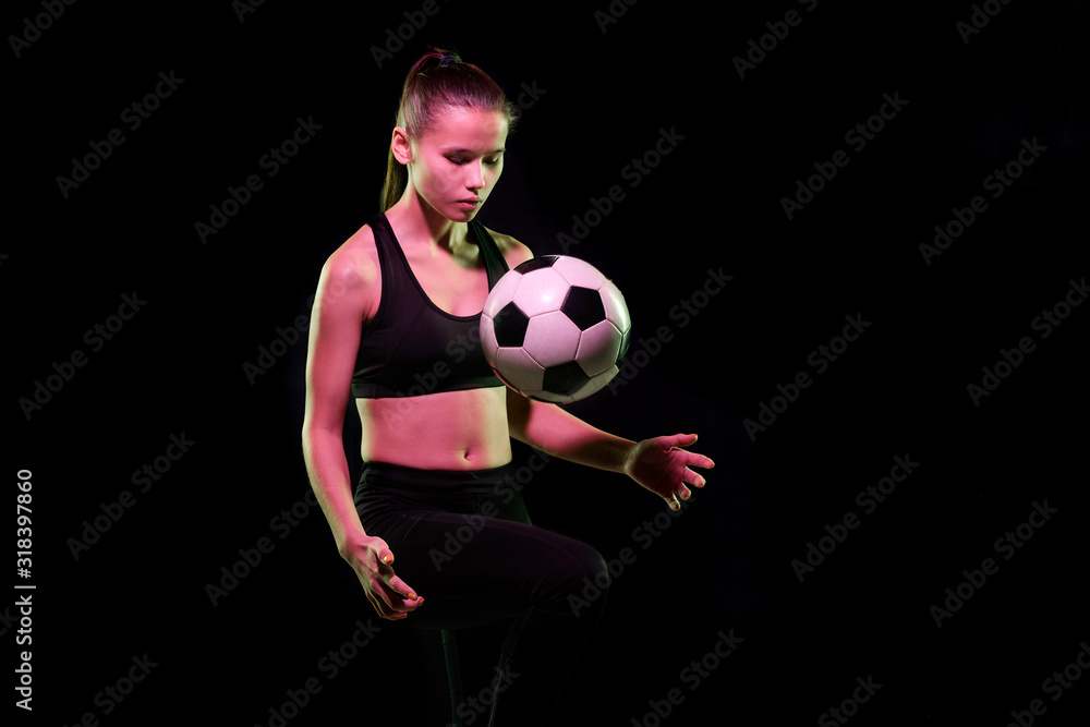 Pretty young female football player in sportswear training with soccer ball Pretty young female football player in sportswear training with soccer ball