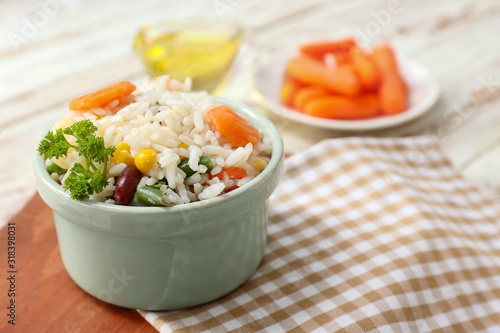 Boiled rice with vegetables in bowl on table