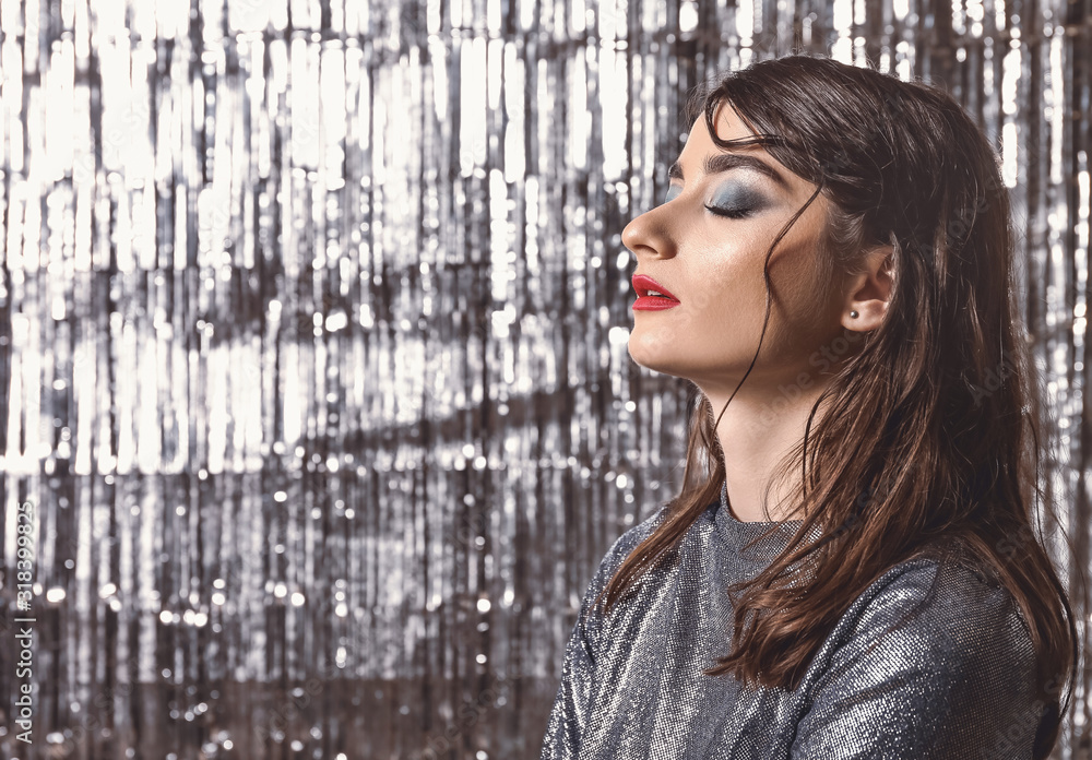Obraz premium Beautiful fashionable woman on shiny silver background