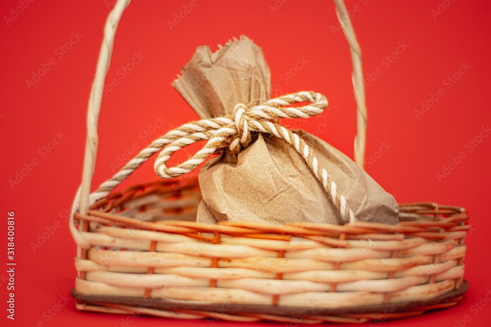 Bolsa de papel en cesto de mimbre regalo atado con cuerda y fondo rojo