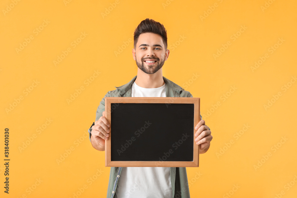 Young man with chalkboard on color background
