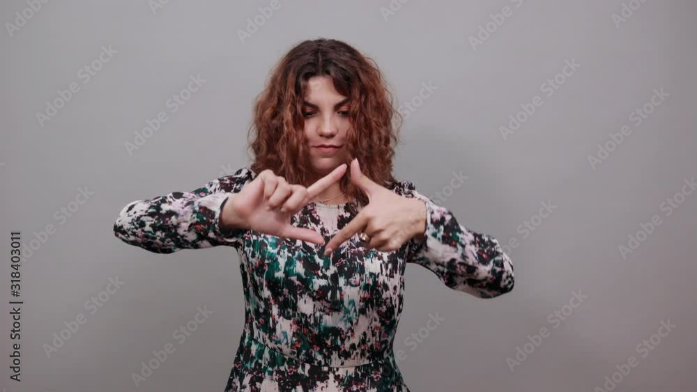 Unhappy charming young lady over isolated gray background in fashion shirt doing frame gesture, looking directly. People emotions. Lifestyle concept Unhappy charming young lady over isolated gray background in fashion shirt doing frame gesture, looking directly. People emotions. Lifestyle concept