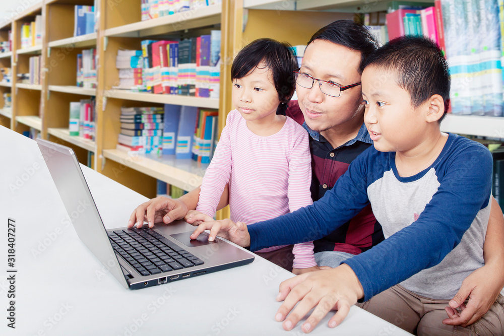 Father helps his children to learn with a laptop