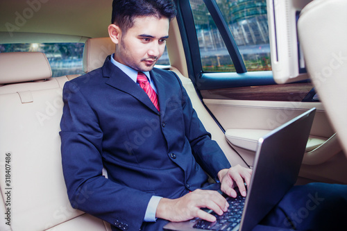 Handsome man looking his laptop inside car © Creativa Images