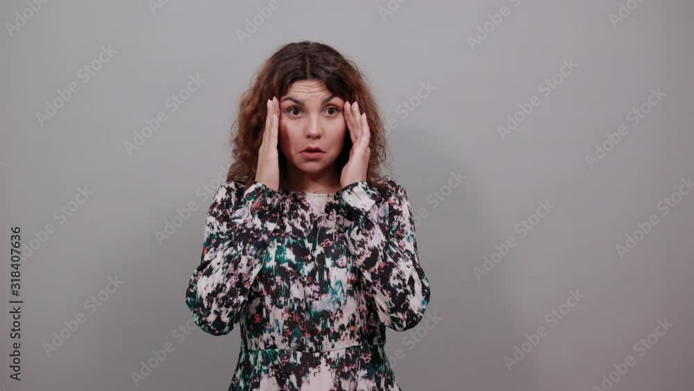 Unhappy young woman keeping fingers on ears, squinting, looking confused over isolated gray background in fashion shirt. People emotions. Lifestyle concept Unhappy young woman keeping fingers on ears, squinting, looking confused over isolated gray background in fashion shirt. People emotions. Lifestyle concept