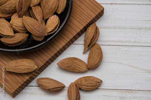 Dried almonds spilled from a dark plate onto a gray background. healthy food for raw foodists and vegetarians. photo