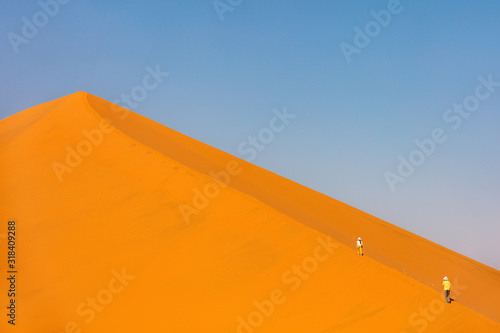 Kids climbing up red sand dune