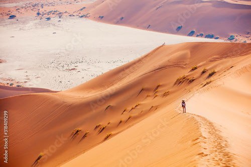 Young woman climbing up red sand dune