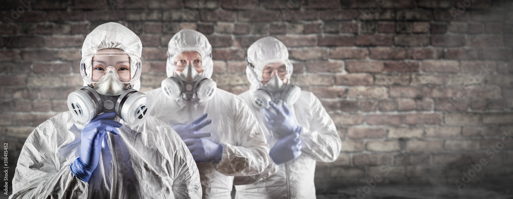 Chinese Woman and Team Behind In Hazmat Suites, Gas Masks and Goggles Against Brick Wall - obrazy, fototapety, plakaty 