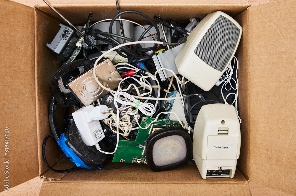 Modern electronic waste in a cardboard box. HDD, power supply, speaker, cable, headphone