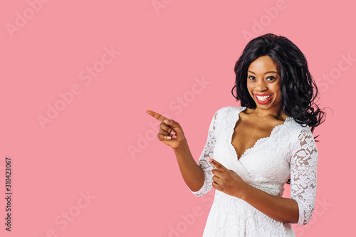 Portrait of  young happy woman in white lace dress pointing to side at copy space