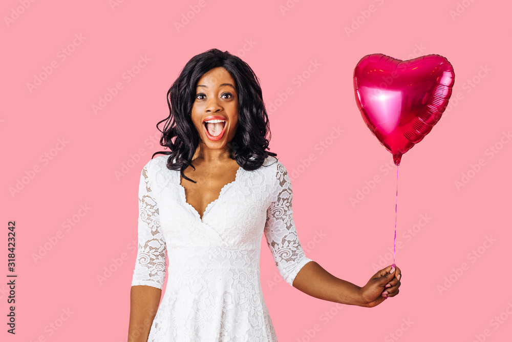 Portrait of an excited young happy woman holding pink heart shaped balloon with big excited smile, valentineÕs day fall in love concept Portrait of an excited young happy woman holding pink heart shaped balloon with big excited smile, valentineÕs day fall in love concept