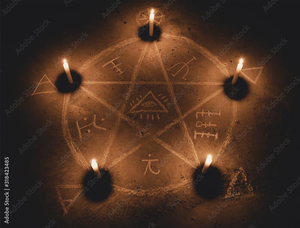 White pentagram symbol on concrete ground. Illuminated with candles ...