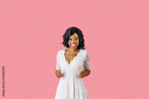 I did it  Portrait of a happy young woman in white dress and black hair smiling while celebrating with closed fists