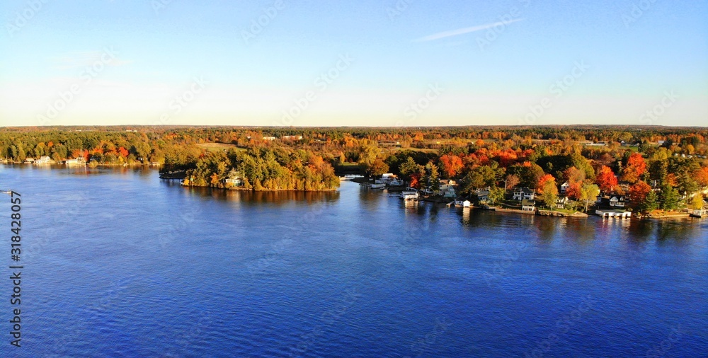Obraz premium The aerial view of the residential area and waterfront homes surrounded by colorful fall foliage near Wellesley Island, New York, U.S.A