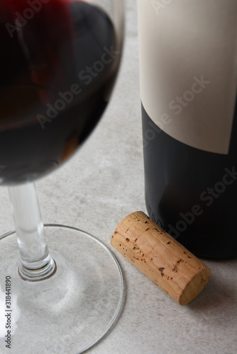 Closeup of a wine cork on a table with wine bottle and wine glass. Focus is on the cork.