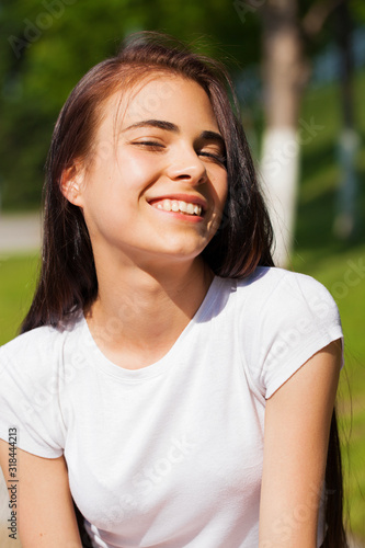 Beautiful brunette woman posing against summer park, bright sunny weather