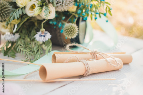 Close up view on two rolled paper sheets with wedding vowes, heart shaped cookies bisquites and bride bouquet decor.