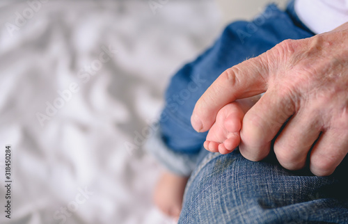 The grandfather holding feet his newborn baby at home in holiday. Family  senior  grandson  baby  grandfather  Happy  lifestyle concept.