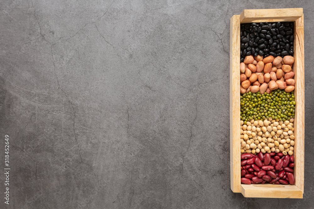 Grains or beans in the wooden tray placed on the black cement floor. Top view. Grains or beans in the wooden tray placed on the black cement floor. Top view.