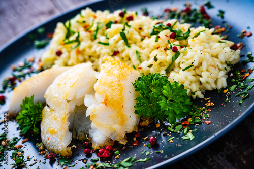 Risotto with fried cod loin on wooden background photo