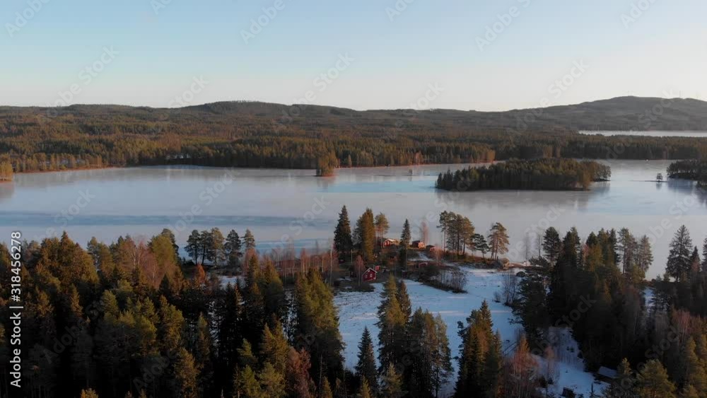 Slowly ascending on a crisp winter day with blue sky with ice coverd lake in the background and group of red houses in Appelbo, Vansbro kommun. Slowly ascending on a crisp winter day with blue sky with ice coverd lake in the background and group of red houses in Appelbo, Vansbro kommun.