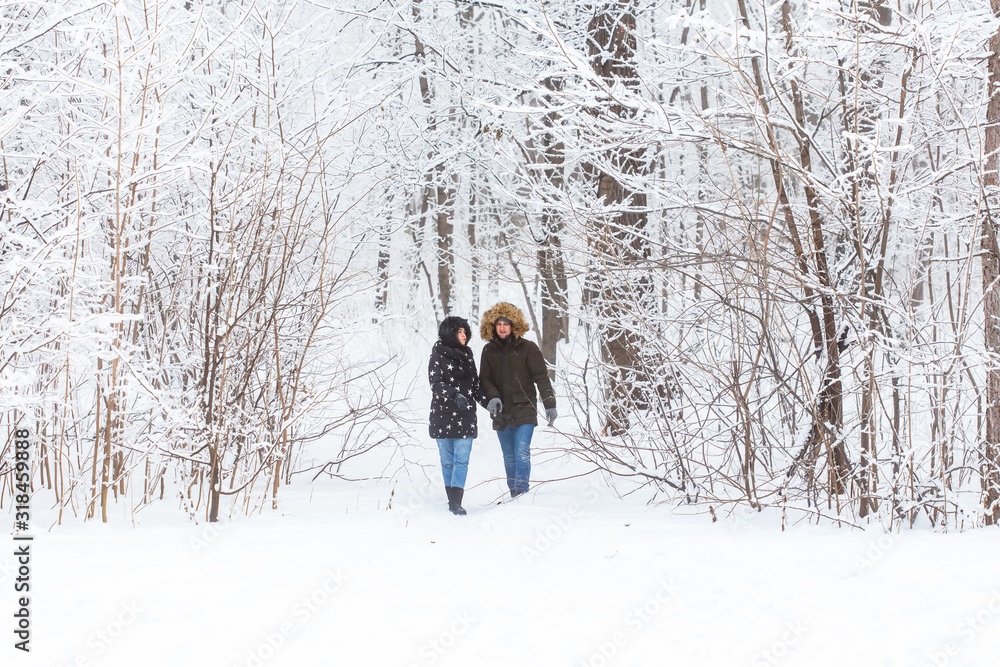 Young couple in love walks in the snowy forest. Active winter holidays.