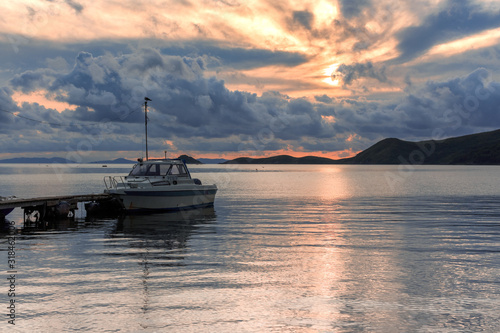 A boat moored near a wooden jetty amid a gorgeous pink and blue sunset.