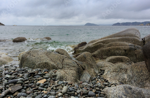 Beautiful sea bay with a rocky shore and clouds, like stones in the water.
