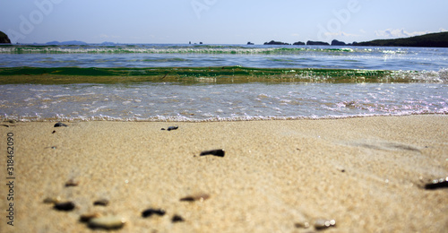 Seascape with waves, sandy beach and rocks on the horizon.